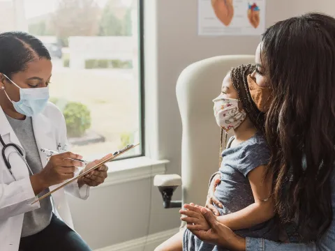Doctor speaks to mother and child in a patient room.