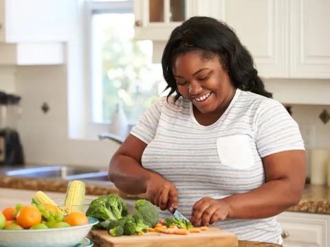 A Woman Chops Vegetables in a Modern Kitchen with a Smile on Her Face.