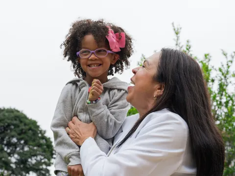 A Little Girl with Glasses is Carried by Her Physician Outside.