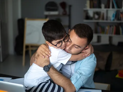 A Father Hugs His Son in a Play Room at Home