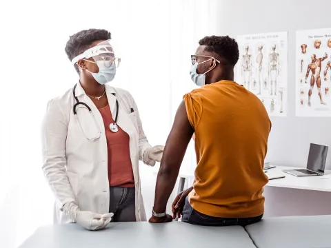 A Doctor Examines Her Patient in an Exam Room while Wearing PPE