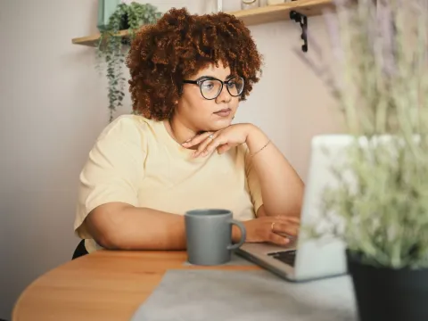 A Woman Explores Her Options on Her Laptop at the Kitchen Table