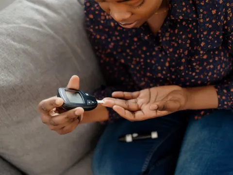 A Woman Tests Her Blood Sugar with a Finger Prick Glucose Device