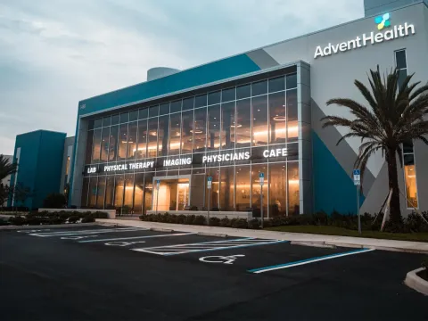 An Exterior Photo of an AdventHealth Health Park Building at Dawn with a Palm Tree in Front.