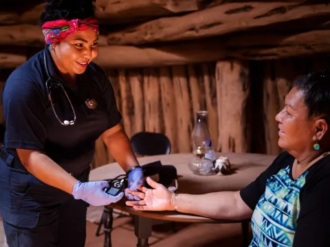 A Native American woman nurse that is about to do a test on a Native American patient.