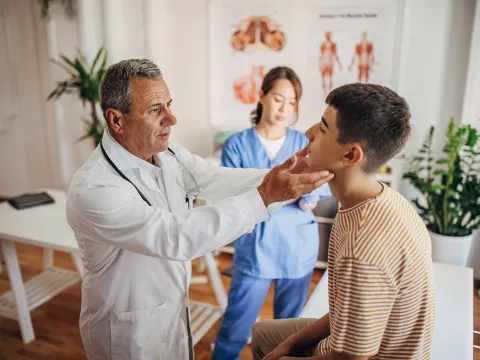 A Doctor Examines a Teenage Patients Face While a Nurse Takes Notes