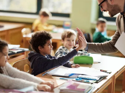 A Student High Fives His Teacher in the Classroom