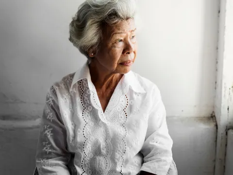 A Senior Woman Stares Out of a Window