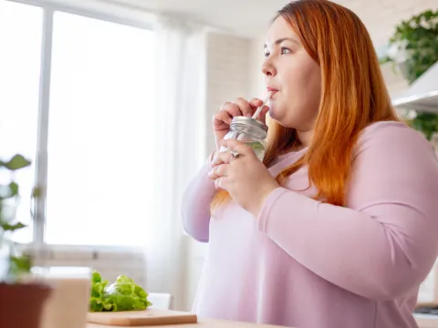 A Woman Drinks Infused Water In Her Kitchen