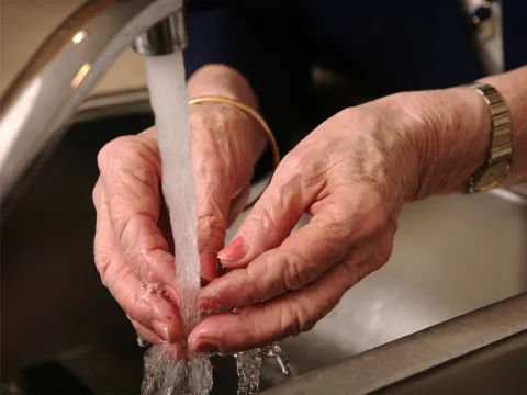 A Close Up of a Senior Woman Washing Her Hands in the Kitchen Sink