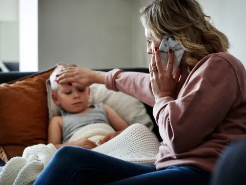 A Mother Checks Her Son's Temperature While on the Phone