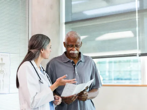 A Doctor Speaks to Her Patient in an Exam Room While Going Over His Treatment Plan.