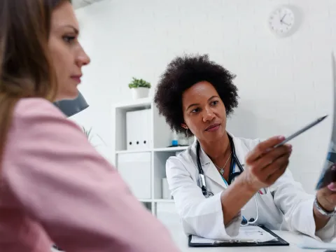 A Doctor Speaks to Her Patient in an Exam Room While Going Over Her Charts.