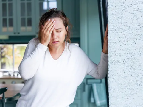 A Woman Holds Her Forehead with a Look of Pain on Her Face