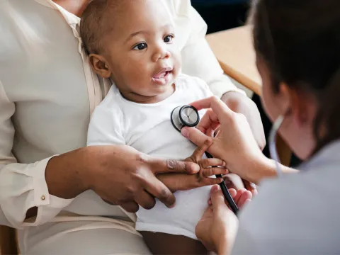 A Physician Checks a Smiling Baby's Breathing with a Stethoscope