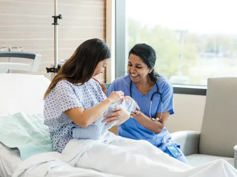 A Patient and a Nurse Laugh and Smile at Her Newborn Baby