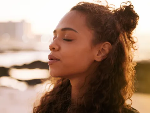 A Woman Stands Outside with Her Eyes Closed, Concentrating on Her Breathing