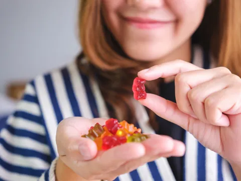 A Woman Smiles as She Selects a Gummy Bear Vitamin