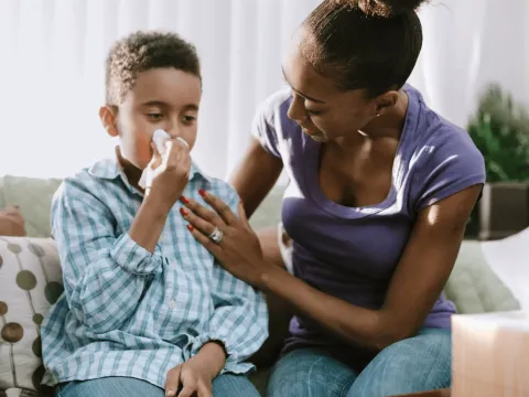 A Mother Checks on Her Son as He Blows His Nose at Home