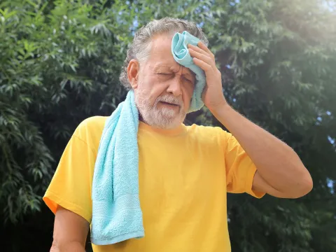 A Senior Wipes His Forehead While Out in the Hot Summer Sun