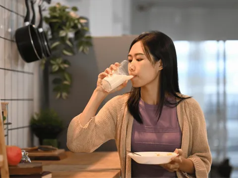 A Woman Drinks a Glass of Milk in Her Kitchen