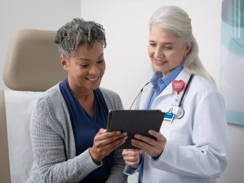 Doctor and patient holding tablet in medical office.