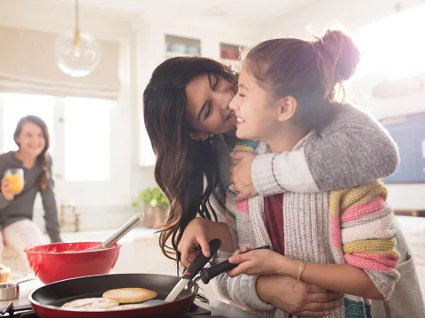 A mother and her teenage daughter enjoying their time cooking breakfast
