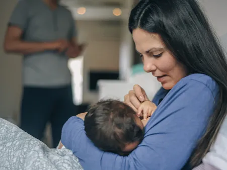 A mother breastfeeds her newborn baby.