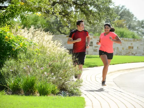 Smiling couple running outside on a sidewalk