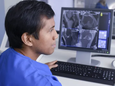 An Asian man examines imaging results on a computer.
