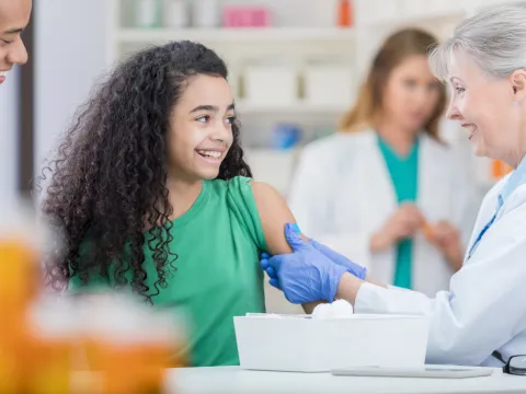 A preteen gets her first HPV vaccine shot from a nurse.