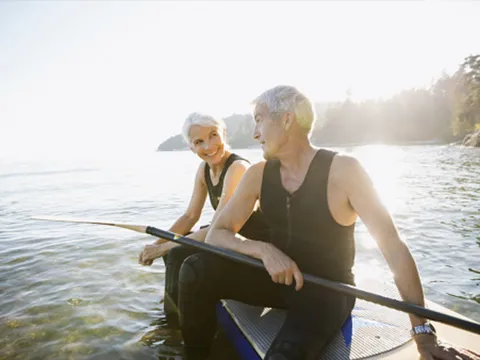 An older Caucasian couple takes the paddleboard on the lake.