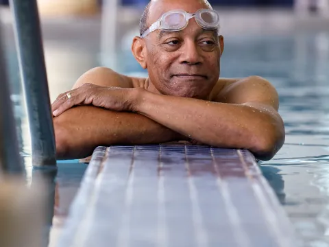 Elderly black man with goggles in a swiming pool.