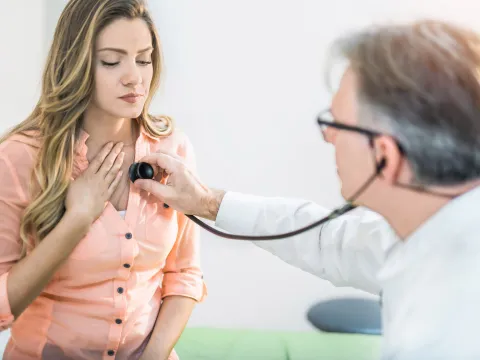 A doctor checking a woman's heart beat.
