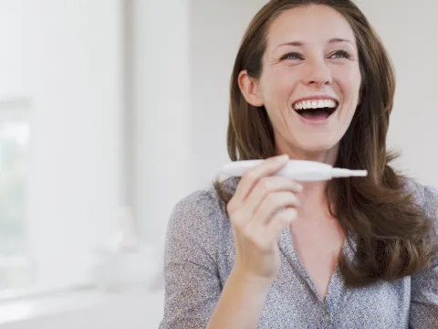 Happy woman laughs at the positive pregnancy test