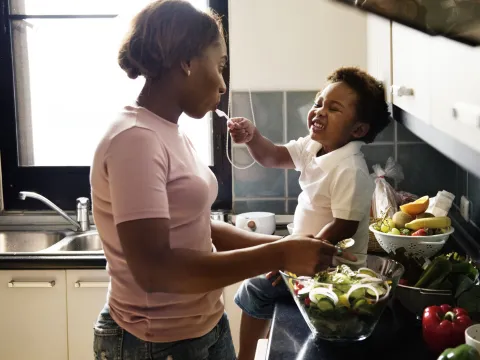A mom prepares a meal for her family with the help of her toddler.
