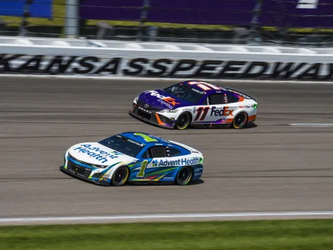 AdventHealth and FedEx NASCAR cars next each other while racing at Kansas Speedway.