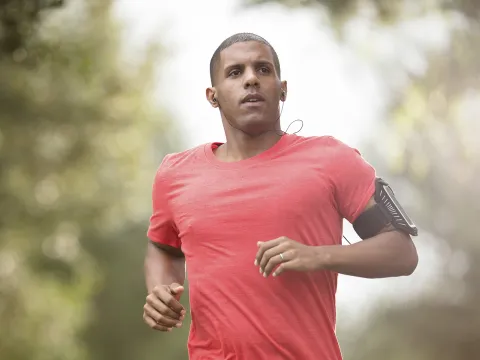 A young man listens to headphones while jogging outdoors