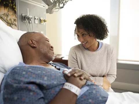 Family member comforting patient in hospital bed.