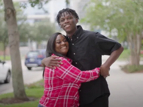 Antonio hugging his mother outside on a sidewalk.