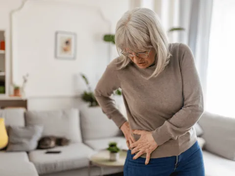 An older woman holds her hip in pain.