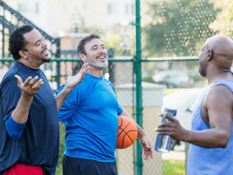 A group of older men talking and taking a break after a round of basketball