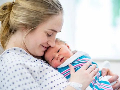 A smiling woman holding her newborn baby.