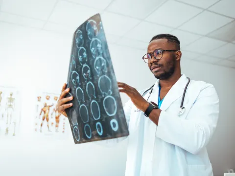 A male doctor holds up a sheet of brain scan images