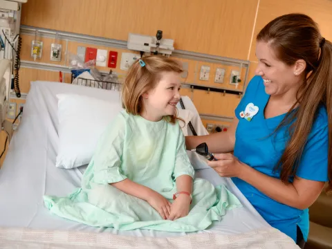 A girl smiles with her nurse