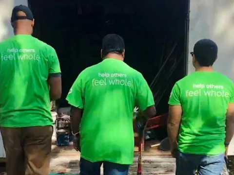 3 volunteers in green shirts facing away from the camera