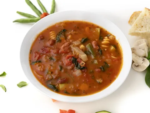 Bowl of minestrone soup with garnishes