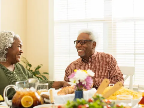An elderly couple sitting at the table, getting ready to eat lunch. 