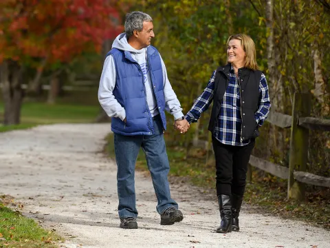 Couple walking down a path outdoors in the fall holding hands.