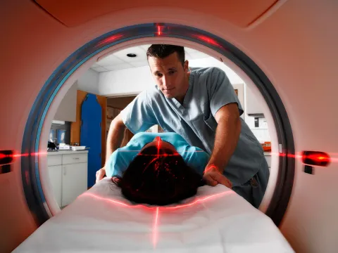 CT tech assisting patient while she gets a scan